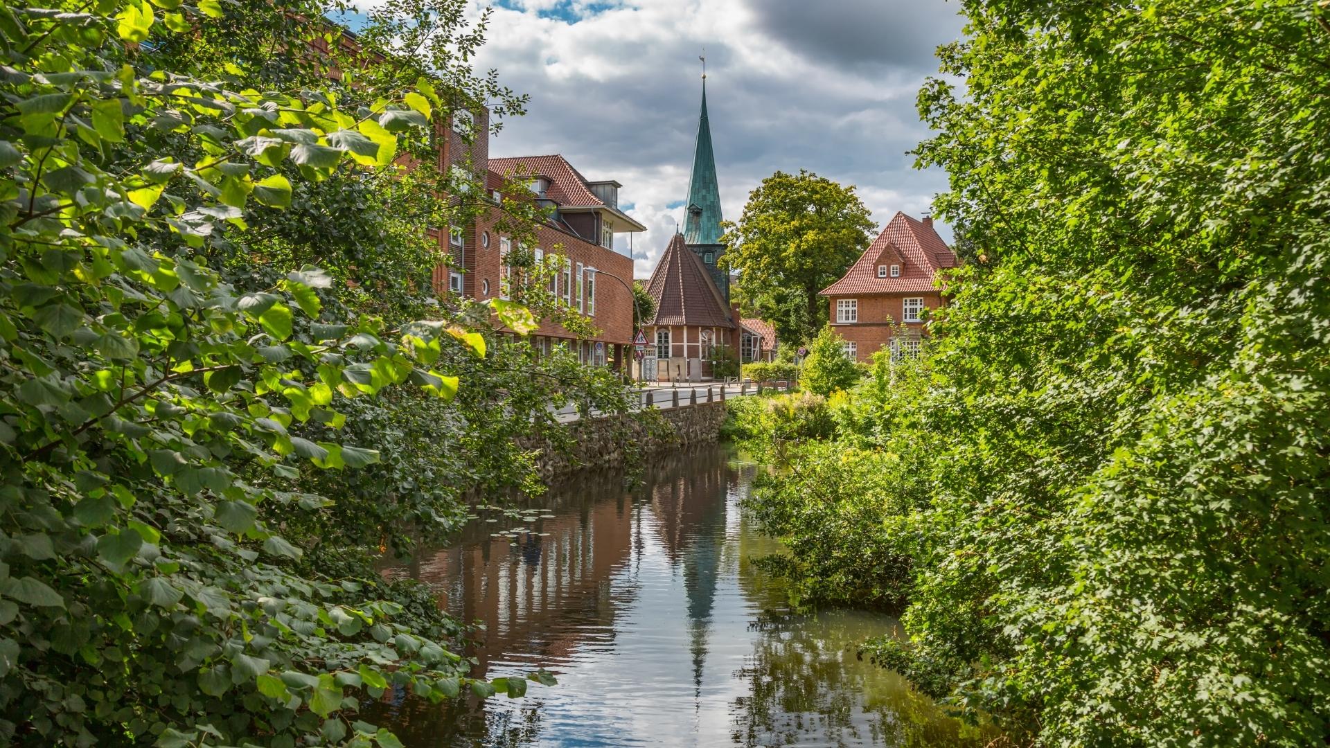 Grüner Wasserlauf mit Backsteinhäusern und Kirchturm in Hamburg-Bergedorf