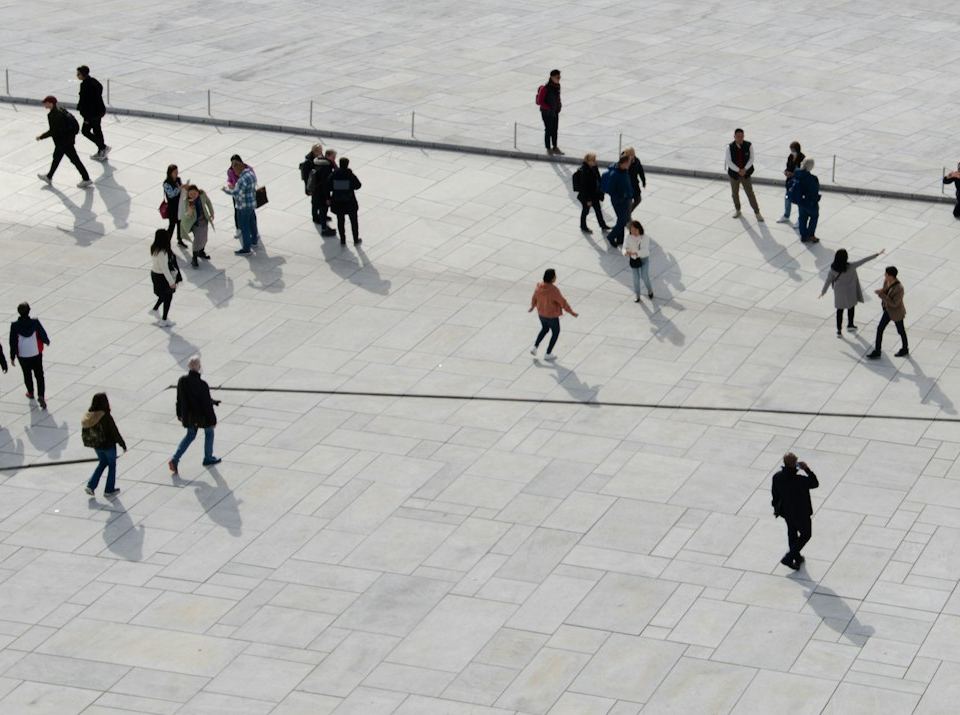 a group of people walking across a cement walkway